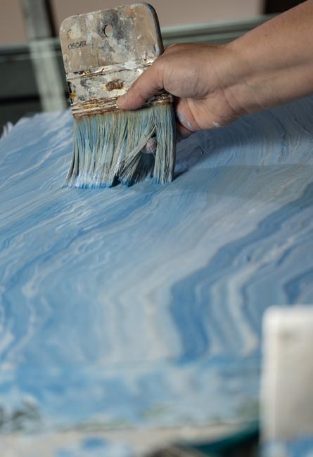 Manual brushstroke of blue glaze on ceramic surface, fluid texture and visible craftsmanship.