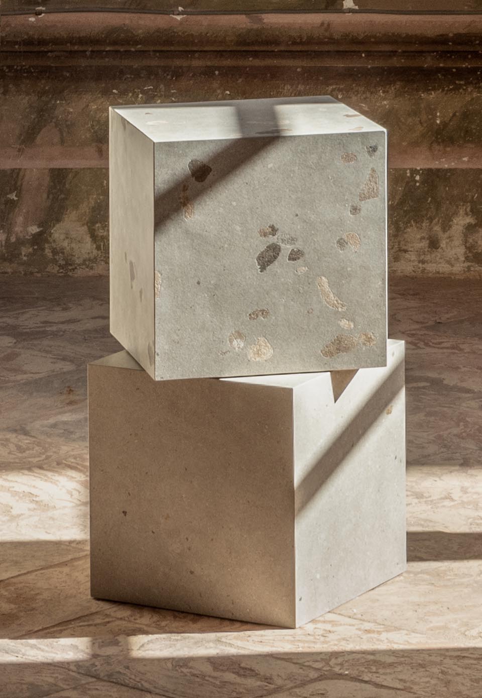 Light stone-effect ceramic cubes with natural inclusions, layered on a textured beige floor.