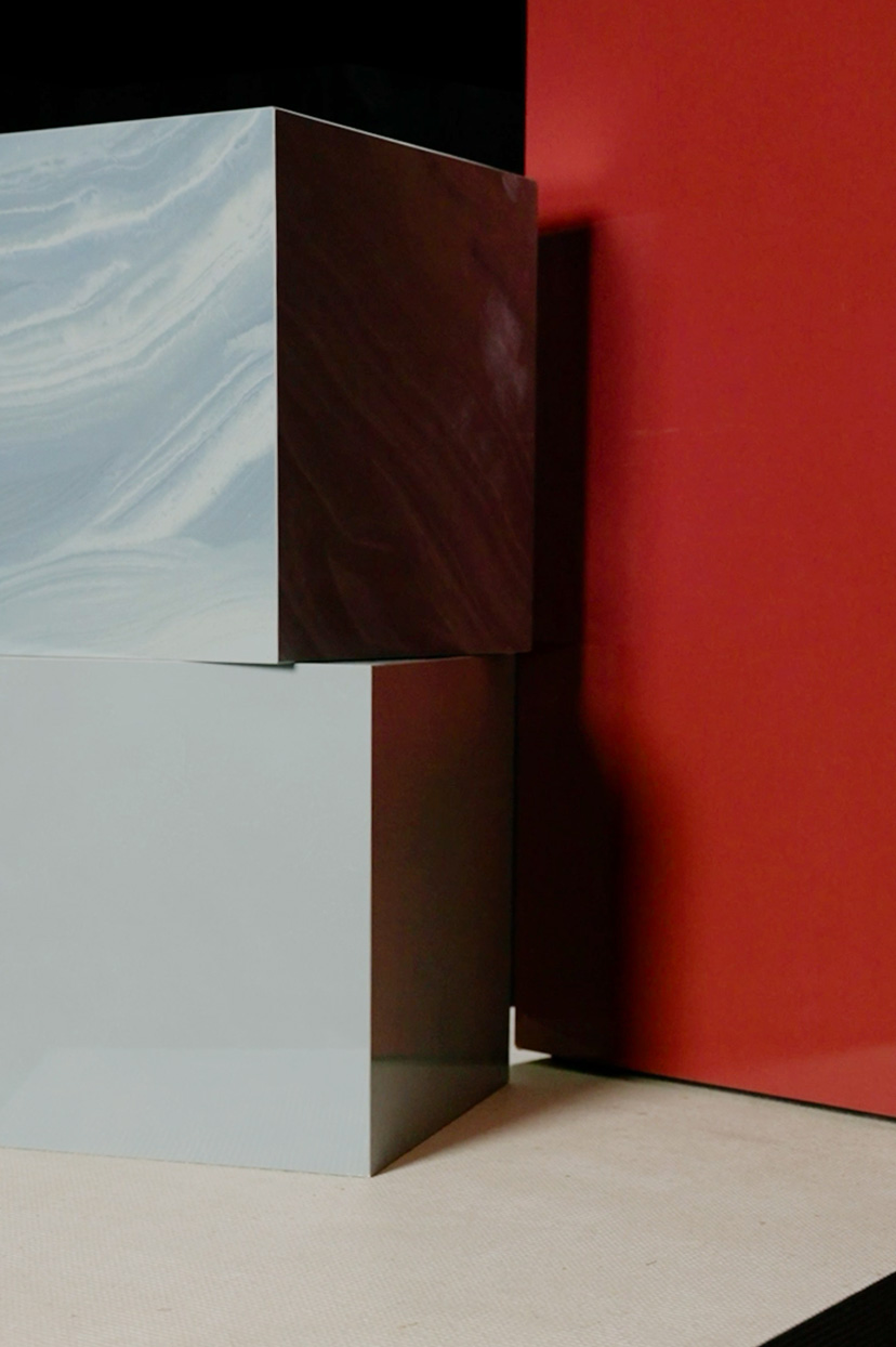 Totem ceramico specchiato con superficie sfumata esposto in ambiente luminoso, riflessi naturali e visitatori sullo sfondo.