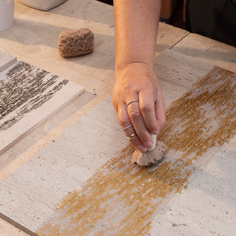 Decoro ceramico artistico con foglia rossa dipinta su fondo beige, effetto materico e pittorico a rilievo.