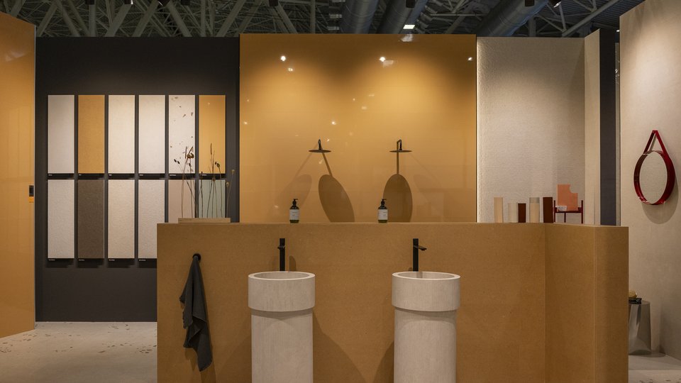 FAP Ceramiche stand with ochre walls and textured panels, cylindrical ceramic washbasins and contemporary design details.
