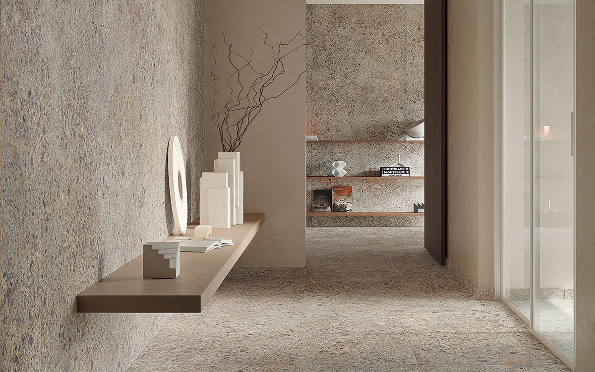 Contemporary setting with beige and grey stone-effect stoneware flooring and walls, taupe-coloured suspended shelf with geometric sculptures in light stone.