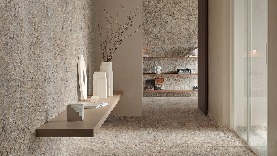 Contemporary setting with beige and grey stone-effect stoneware flooring and walls, taupe-coloured suspended shelf with geometric sculptures in light stone.