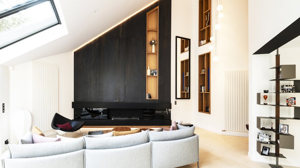 Современная гостиная с белыми стенами и темными панелями, серым диваном и яркими деталями для элегантного и минималистичного дизайна.